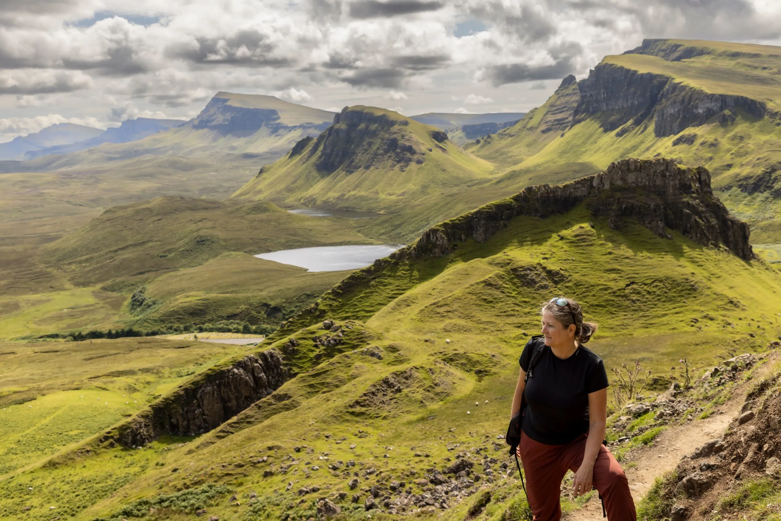 woman hiking on mountain range Quiraing. It is a geological formation on the Scottish Isle of Skye and a hiker's paradise